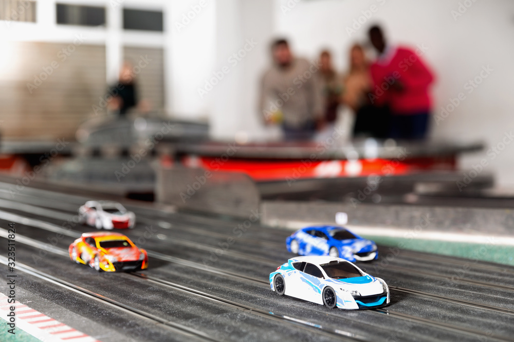 Slot car racing track. Emotional players drive toy cars