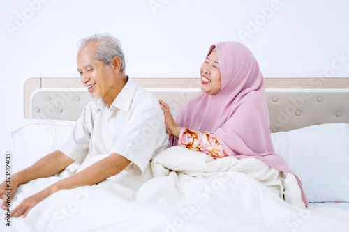 Elderly muslim woman massaging her husband back