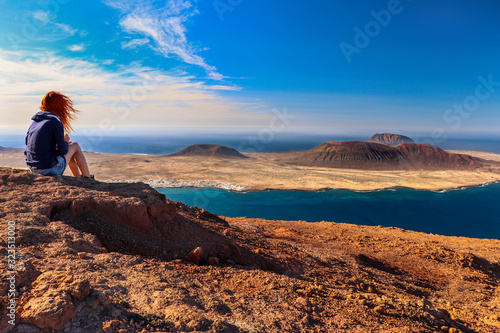 A woman looking at the sea and the island. Location: Europe, Spain, Canary Islands, Lanzarote (near Mirador del Rio; La Graciosa island in the background) photo