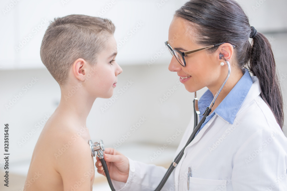 Young female doctor pediatrician examines boy patient with stethoscope Young female doctor pediatrician examines boy patient with stethoscope