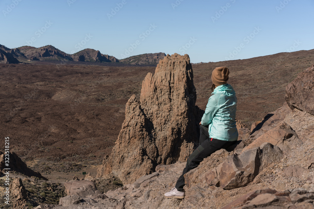 Woman in bright blue jacket  the beautiful volcanic valley with mountains on the background during. Winter traveling on Tenerife island, Spain