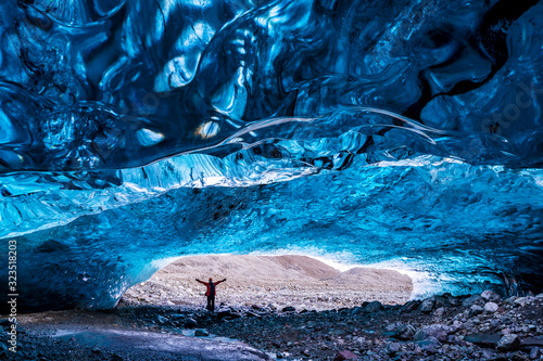 Woman stands in the opening of an ice cave in the Vatnajokull glacier in southeast Iceland