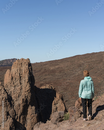 Woman in bright blue jacket the beautiful volcanic valley with mountains on the background during. Winter traveling on Tenerife island, Spain