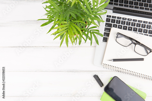 Business concept - Top view of white desktop background with notebook, smart phone, plant and clip for mockup design