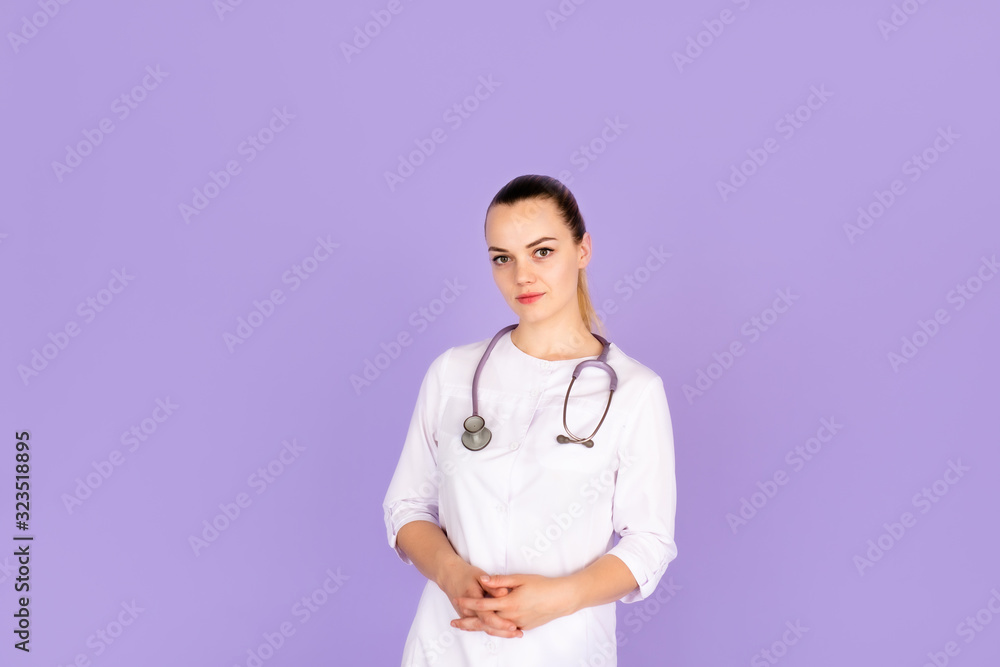 Medical concept of beautiful female doctor in white coat with phonendoscope. Medical student general practitioner. Woman hospital worker looking at camera and smiling, studio, purple background. Medical concept of beautiful female doctor in white coat with phonendoscope. Medical student general practitioner. Woman hospital worker looking at camera and smiling, studio, purple background.