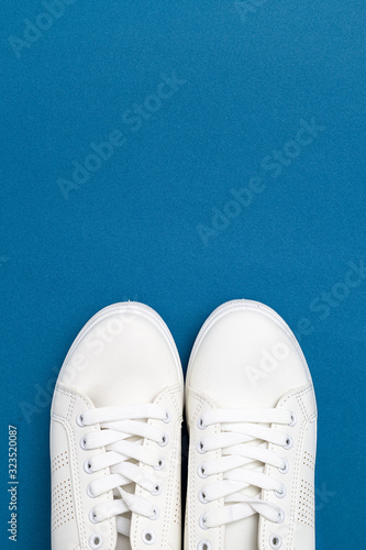 White sneakers on blue backfground. Copy space. Vertical photo