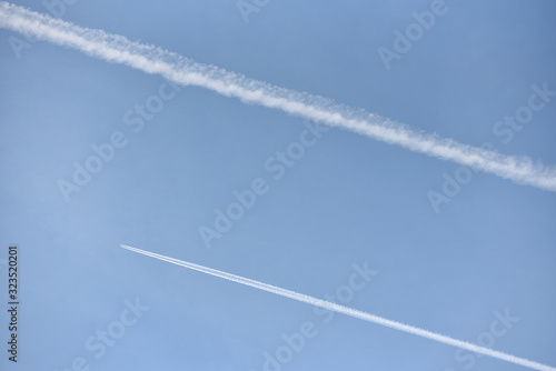 A passenger plane flies high in the sky and leaves a white trail against the blue sky. Text space © pridannikov