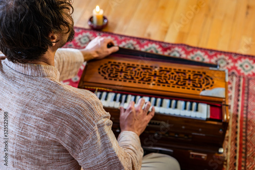 Bild auf Leinwand Rear view of young shamanic male musician playing harmonium for sacred and kirta
