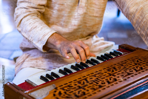 Foto Closeup of shamanic male hands on harmonium keys playing sacred kirtan music for