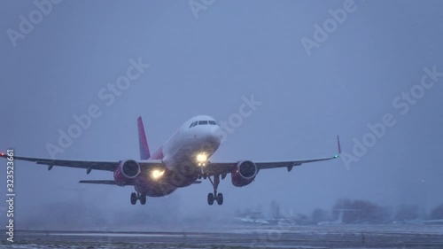 Airplane (aircraft) taking off in a heavy evening blizzard (snowstorm)