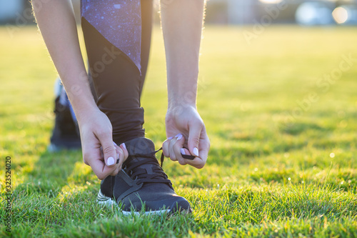 Close-up of female hands tying shoelace on running shoes before practice. Runner getting ready for training. Sport active lifestyle concept.