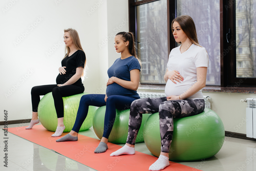 Obraz premium A group of young pregnant mothers are engaged in Pilates and ball sports at a fitness club. Pregnant