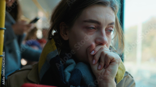 Tableau sur toile Face sick woman use phone coughs sneezes on the tram look at camera cold autumn