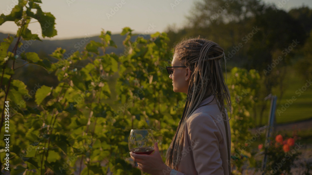 Stylish woman walk vineyards with glass of red wine smile feel happy organic connecting with nature agriculture sunny travel countryside field grape green rural view tasting slow motion Stylish woman walk vineyards with glass of red wine smile feel happy organic connecting with nature agriculture sunny travel countryside field grape green rural view tasting slow motion