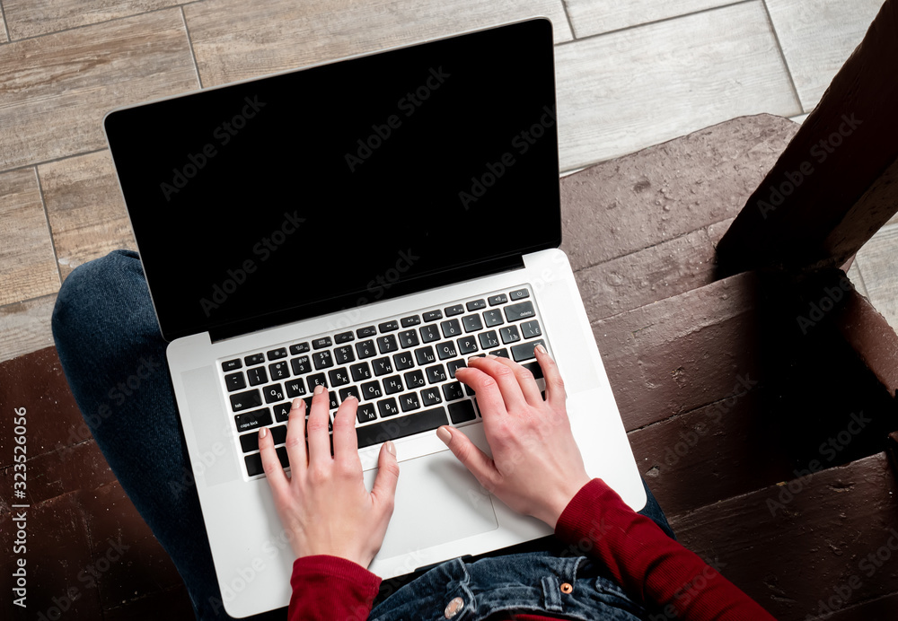 hipster with laptop computer sits on aged stairs in old country house
