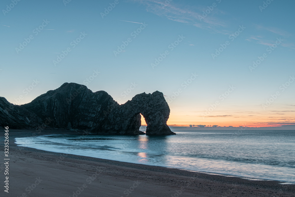 A photograph of Durdle door and crashing waves taken at dawn