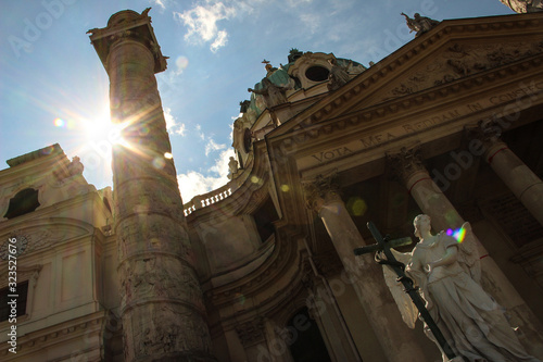 Oblique angle of the ancient St. Charles Church and a sun flare behind the Trajan's column. Karlskirche main facade. Vienna, Austria. photo