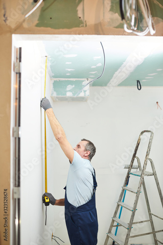Valokuva Side view portrait of senior construction worker measuring wall while renovating