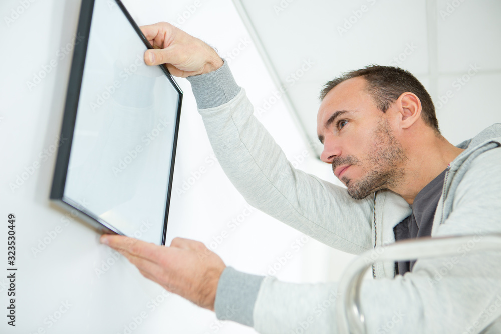 man hanging a blank frame on the wall