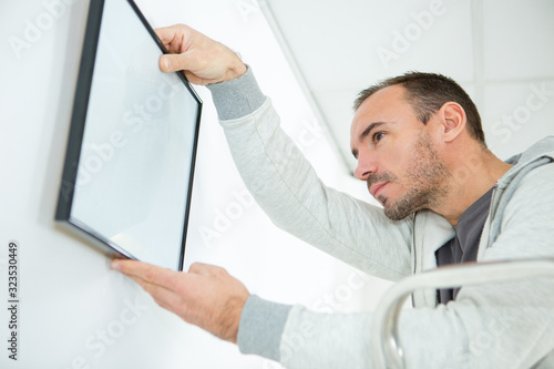 man hanging a blank frame on the wall