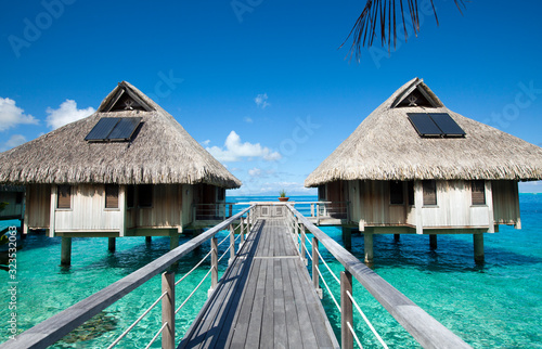 Wooden walkways over the water of the blue tropical sea to authentic traditional Polynesian thatched roof houses