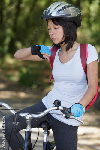 woman biker with mountain bike looking at her watch