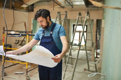 Foto Portrait of bearded construction worker looking at floor plans while renovating
