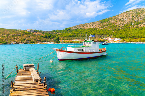 Wooden pier and colourful Greek fishing boat on turquoise sea in Posidonio bay, Samos island, Greece photo