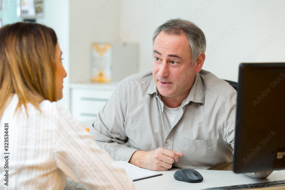 Obraz premium woman in consultation with mature man sat at office desk