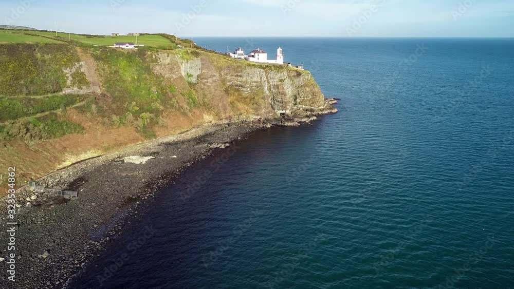 Blackhead Lighthouse in Whitehead village near Carrickfergus and Belfast on a steep cliff with coastal walking path on the Atlantic coast in County Antrim, Northern Ireland, UK. Aerial approach video Blackhead Lighthouse in Whitehead village near Carrickfergus and Belfast on a steep cliff with coastal walking path on the Atlantic coast in County Antrim, Northern Ireland, UK. Aerial approach video