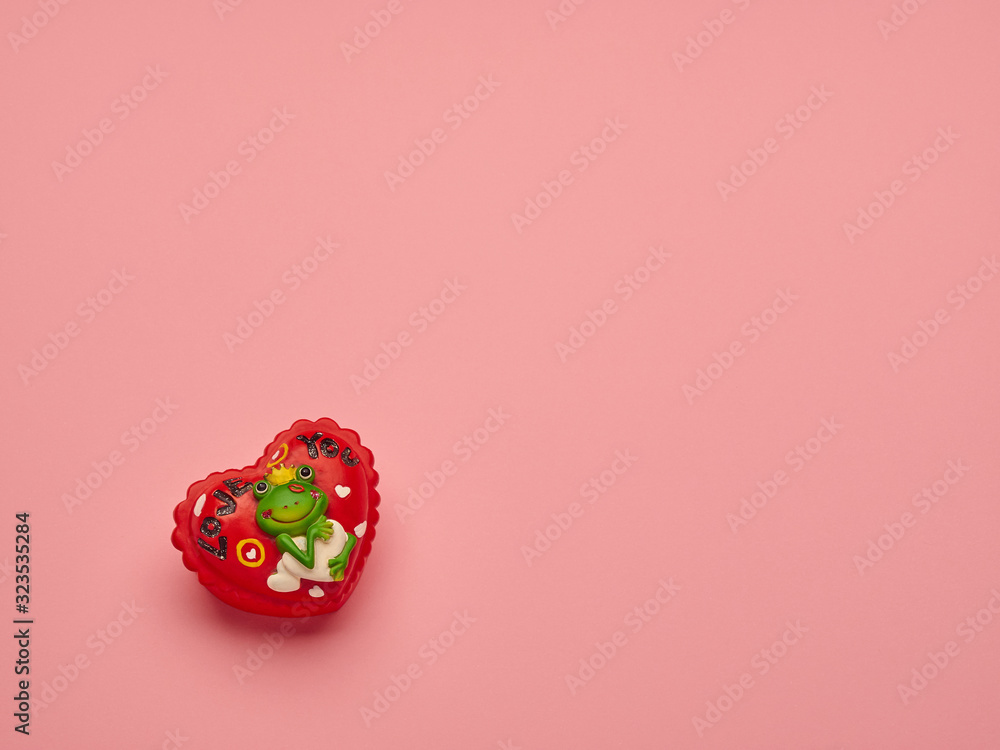 Red heart figure with fall in love frog on a pink background with copy space. Valentine's Day. Red heart figure with fall in love frog on a pink background with copy space. Valentine's Day.