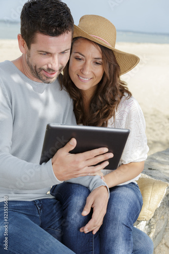 couple looking at a tablet by the seaside