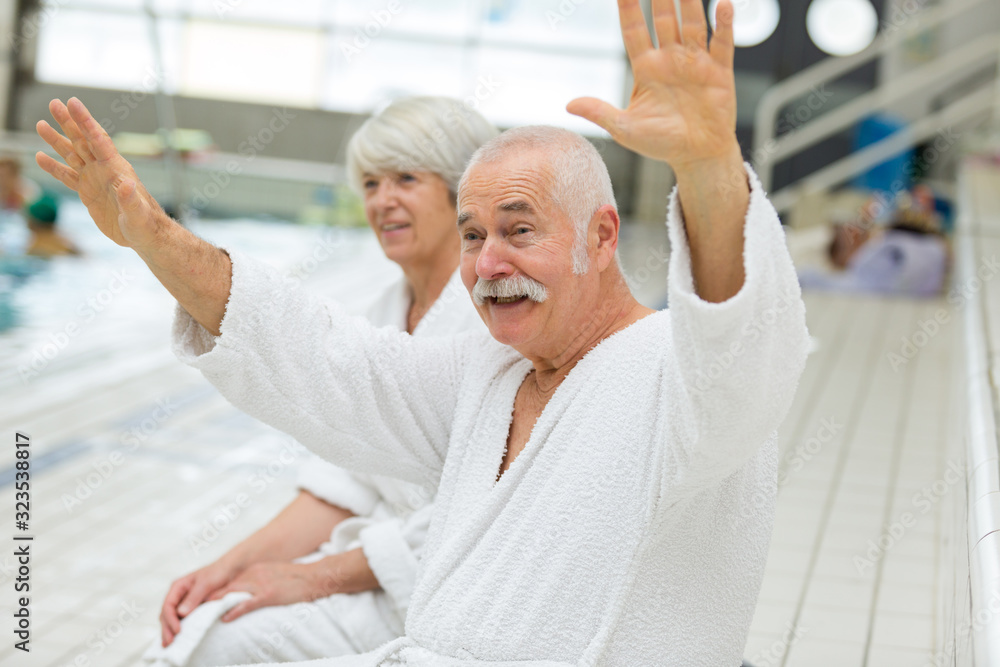 Obraz premium senior couple in bathrobe waving at someone