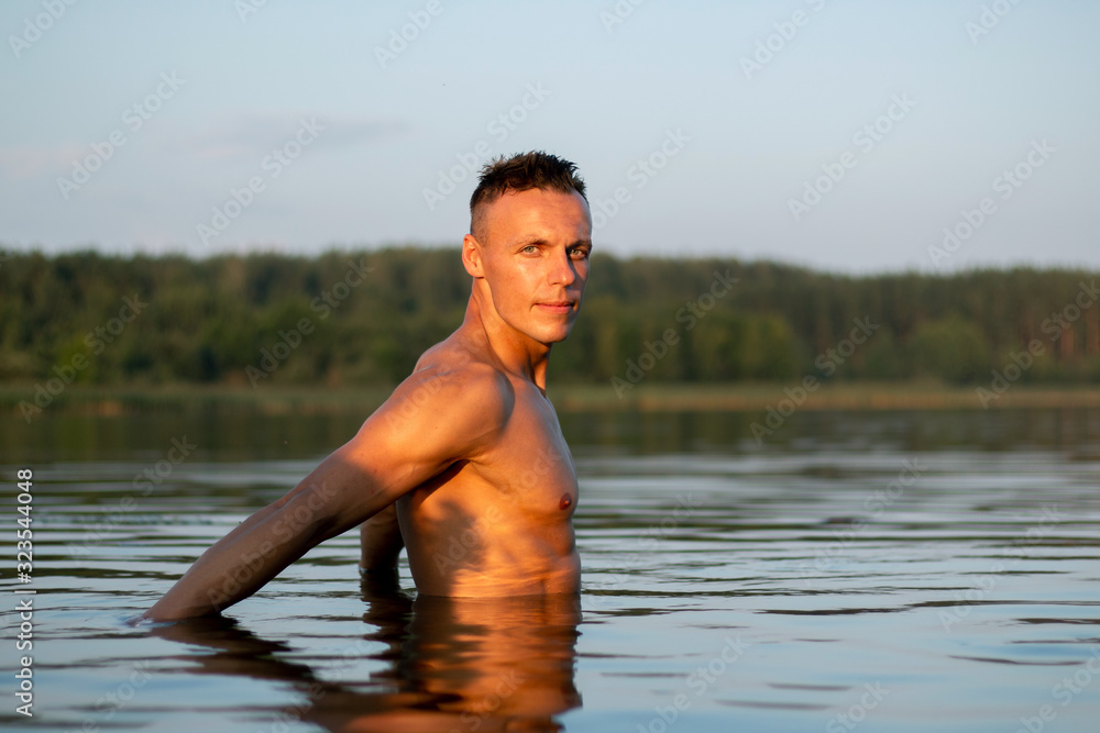 Fototapeta premium A beautiful muscular man on a lake in the water.