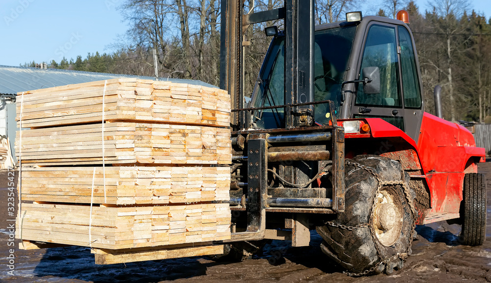 Fototapeta premium The loader picks up and stacks the lumber