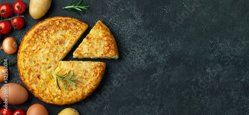 Spanish omelette with potatoes and onion, typical Spanish cuisine on a black concrete background. Tortilla espanola. Top view with copy space photo