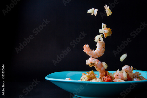 Ceviche de camarón, Foto con camarones callendo al plato, camarones y verduras.  photo
