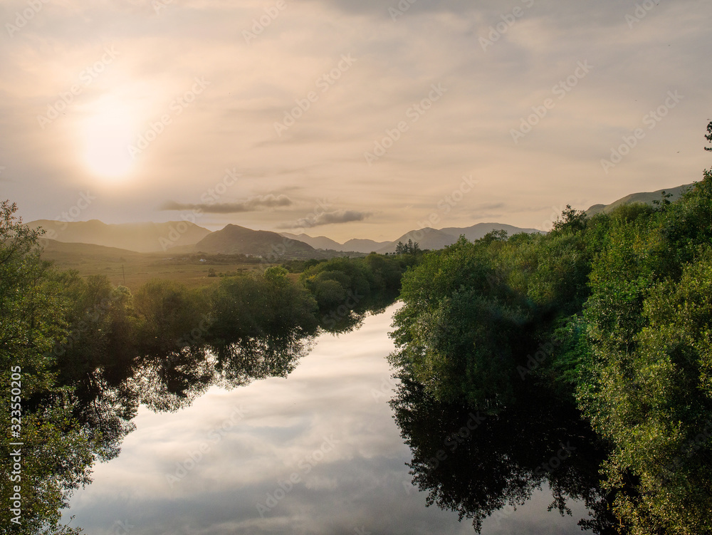 Sunset over mountains in Connemara, county Galway. Small calm river with trees. Peaceful atmosphere.