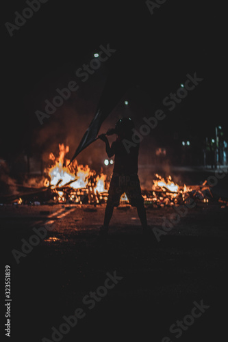  man waving night flag in protest with fire