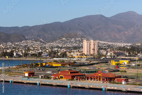 Ensenada, Mexico - January 17, 2012: Closeup of Red Cruise Terminal at pier of harbor with cityscape on slope of mountain in back and behind blue bay water. Pink Villa Marina Hotel towers over all els photo