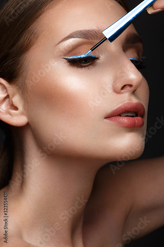 Beautiful girl with sexy lips and classic makeup with cosmetic blue eyeliner in hand. Beauty face.