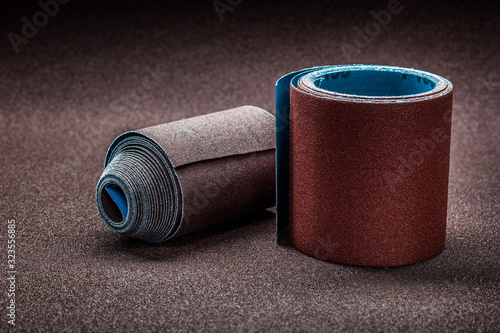 Obraz na płótnie big rolls of abrasive paper on background of biggest sheet of sandpaper