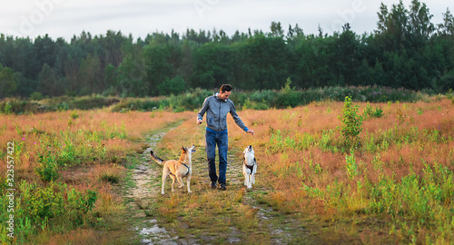 Young guy training dogs in countryside at nature