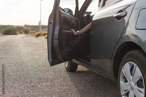 Woman with opened door getting out of the carn on the road