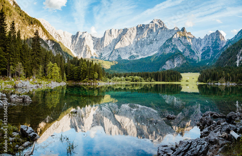 Beautiful morning scene with alpine peaks reflecting in tranquil mountain lake at sunrise