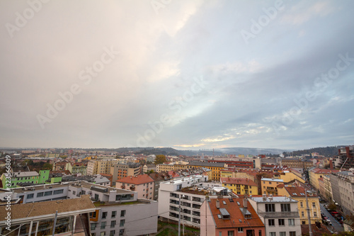 Aerial panorama of Brno, Czech Republic, with a focus on a residential suburb with panelaky towers in background, from the roofs of houses. Brno is the second biggest Czech city
