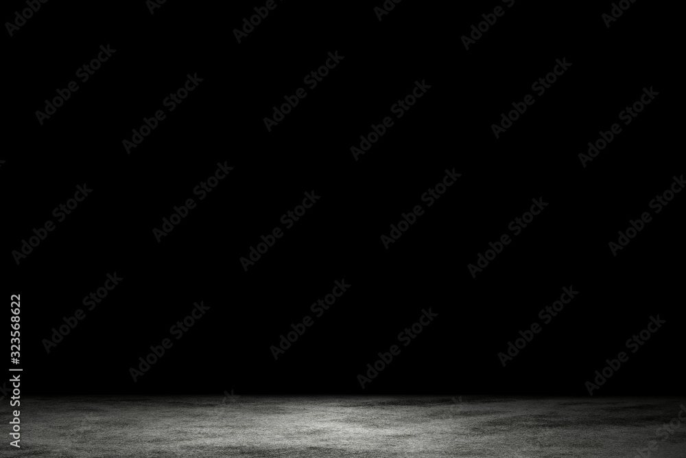 Fototapeta Light shining down on dirt gray cement floor in dark room with copy space, abstract background