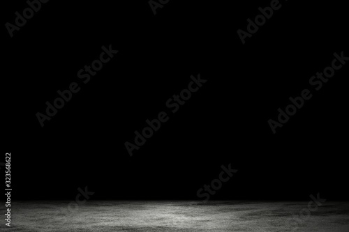 Light shining down on dirt gray cement floor in dark room with copy space, abstract background