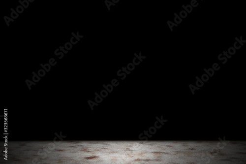 Light shining down on dirt concrete floor in dark room with copy space, abstract background