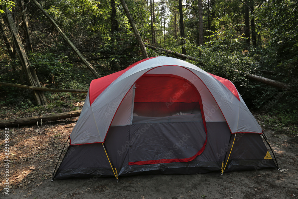 A red and gray tent setup in the woods.